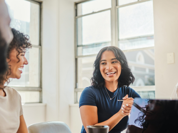 Four people in a conference room smiling at each other.