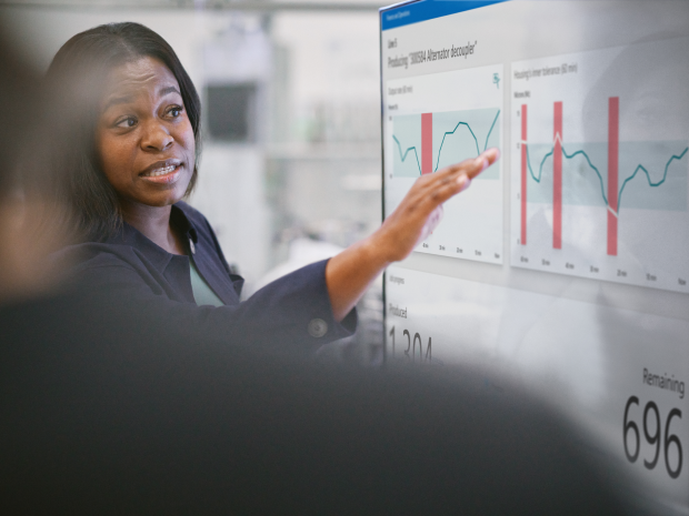 A person presenting a chart on a large screen to colleagues